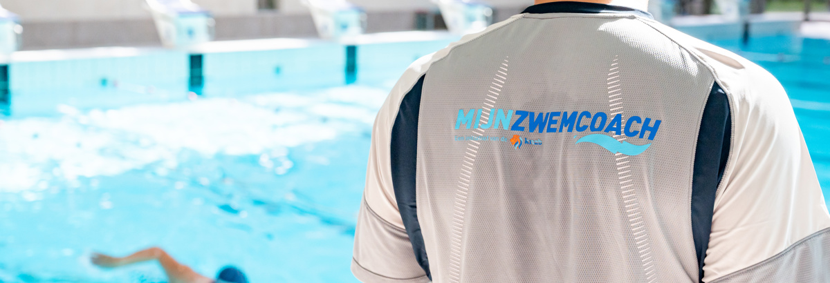 Trainer kijkt op het water waarin zwemmers cursus volen